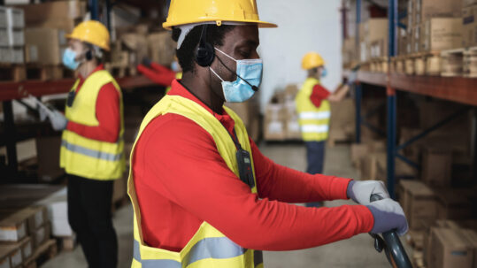 warehouse worker loading delivery boxes while wearing mask