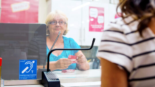 Woman speaks to a staff member using a hearing loop