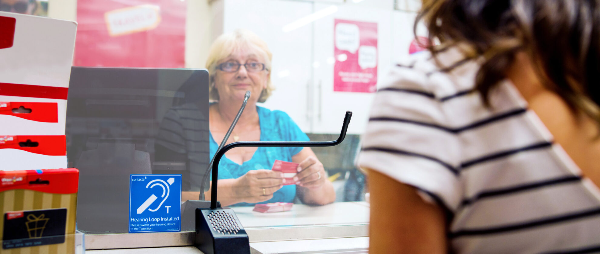 Woman speaks to a staff member using a hearing loop