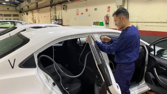 Taxi driver installing hearing loop sign to taxi window