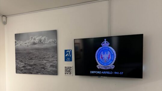 Hearing loop facility sign on the wall at RAF Defford Museum